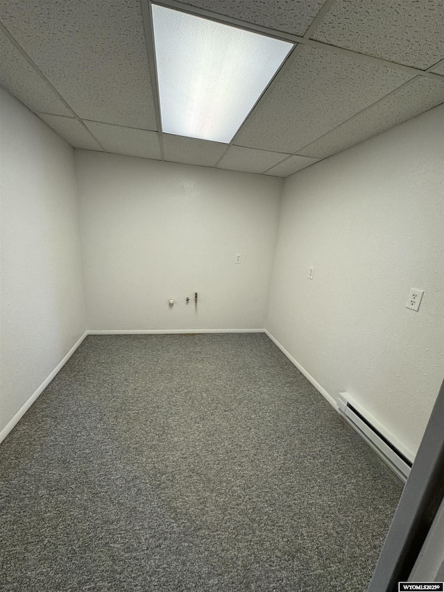 basement with a drop ceiling, a baseboard radiator, and carpet flooring