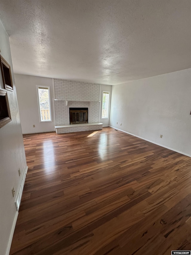 unfurnished living room featuring a textured ceiling, dark wood-type flooring, and a fireplace