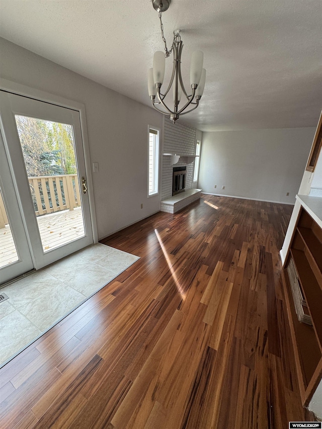 unfurnished living room featuring hardwood / wood-style floors, an inviting chandelier, and a fireplace