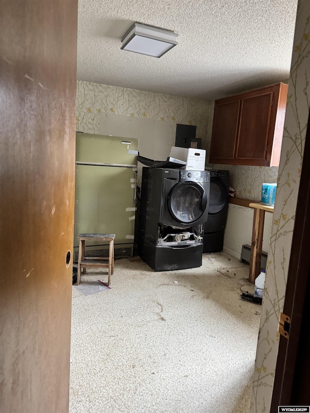 laundry room with cabinets, washing machine and dryer, and a textured ceiling