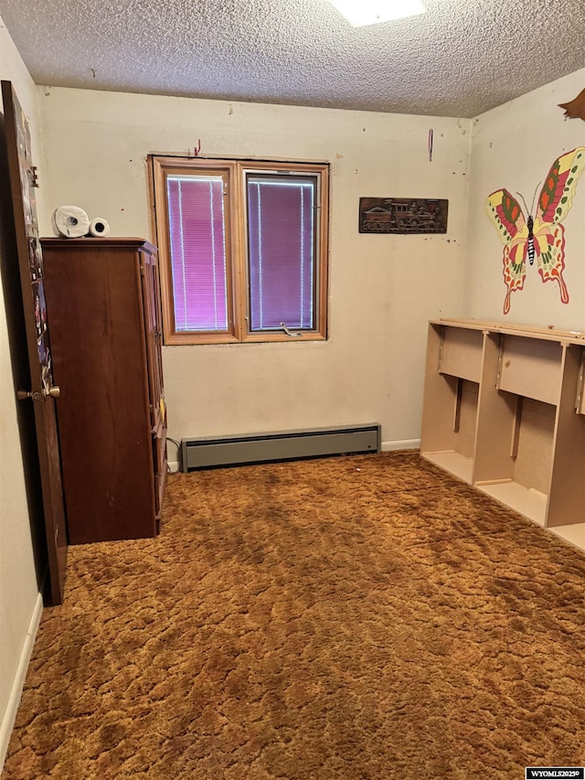 spare room with dark carpet, a textured ceiling, and a baseboard heating unit