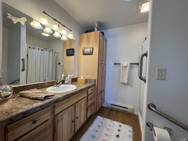 bathroom with hardwood / wood-style floors, vanity, and a baseboard radiator