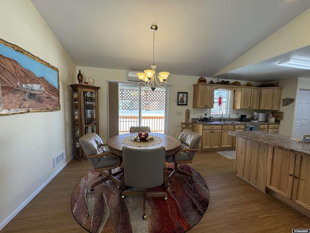 dining area featuring sink, wood-type flooring, a notable chandelier, and vaulted ceiling