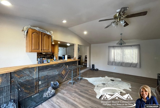 kitchen with ceiling fan, vaulted ceiling, sink, and hardwood / wood-style flooring