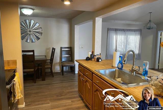 kitchen with stove, wood-type flooring, a textured ceiling, pendant lighting, and sink