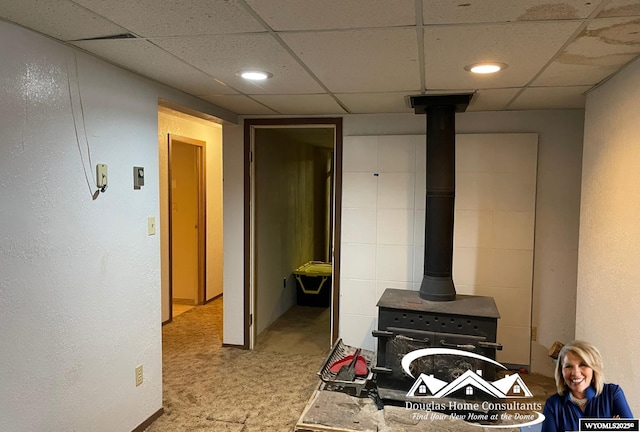 interior space featuring a wood stove and a drop ceiling