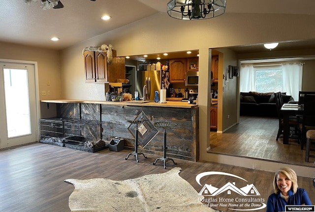 kitchen with dark hardwood / wood-style floors, lofted ceiling, stainless steel appliances, and an inviting chandelier