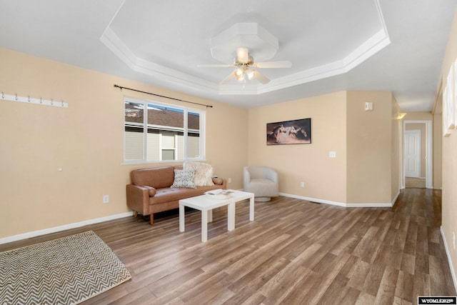 sitting room with wood finished floors, a raised ceiling, and baseboards