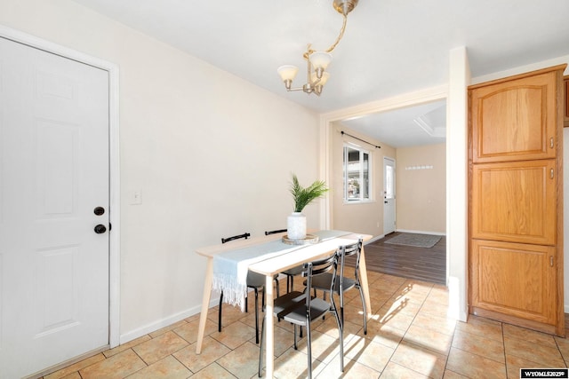 dining area featuring light tile patterned floors, baseboards, and a chandelier