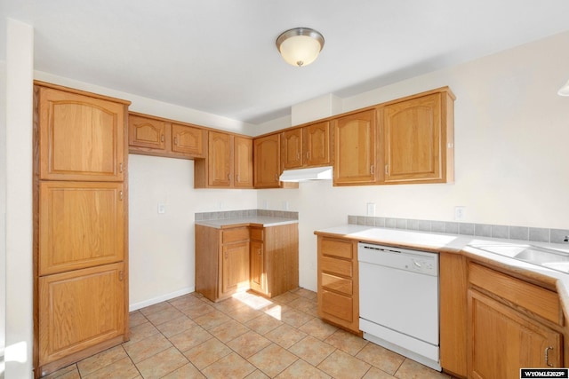 kitchen with light tile patterned floors, light countertops, a sink, dishwasher, and under cabinet range hood