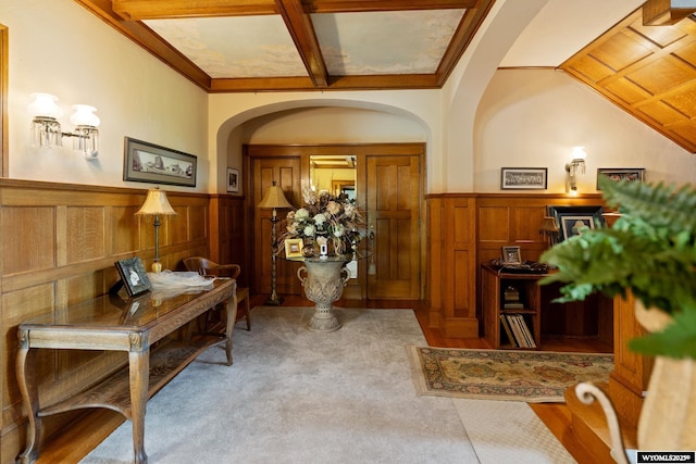 entrance foyer featuring wood walls, light carpet, and beamed ceiling