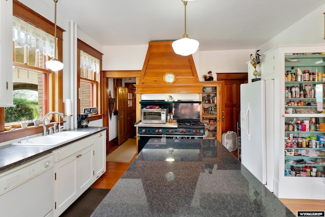 kitchen with white appliances, white cabinets, decorative light fixtures, premium range hood, and sink