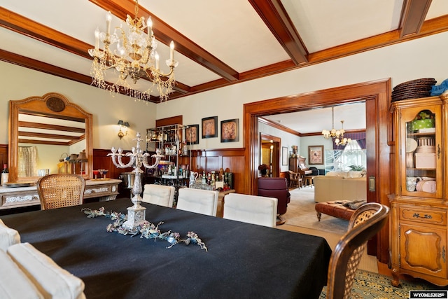 dining area with wood walls, ornamental molding, beamed ceiling, and an inviting chandelier