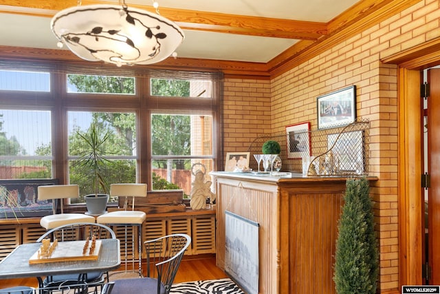 interior space featuring hardwood / wood-style floors, a healthy amount of sunlight, beamed ceiling, and brick wall