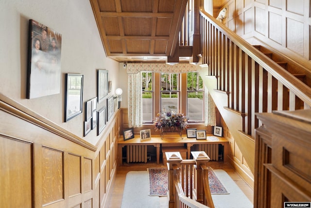 stairway with wooden ceiling, radiator, beam ceiling, and coffered ceiling