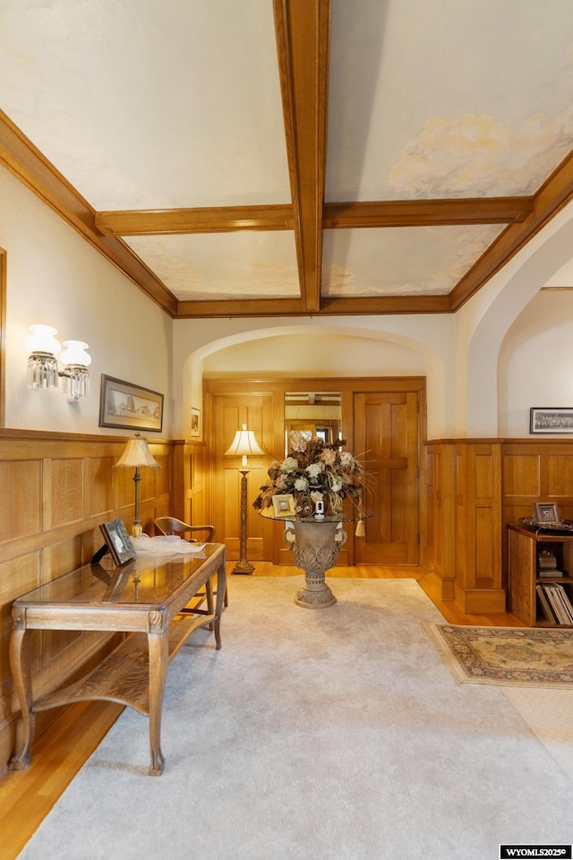 office area featuring coffered ceiling, light colored carpet, beam ceiling, and wooden walls