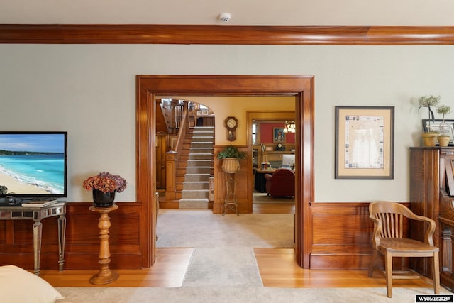 interior space with light carpet, wooden walls, and ornamental molding