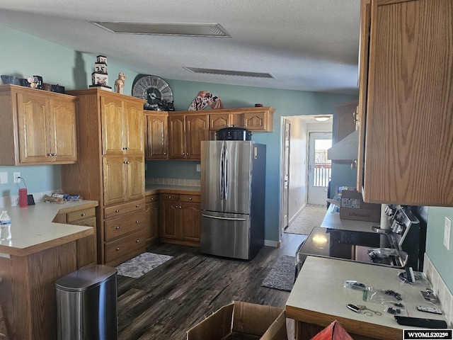 kitchen featuring dark hardwood / wood-style flooring, wall chimney exhaust hood, a textured ceiling, electric range, and stainless steel refrigerator