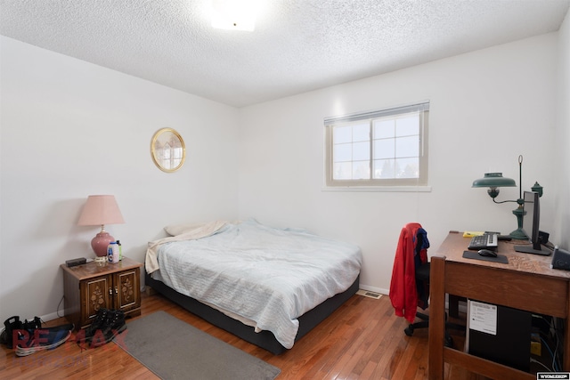 bedroom featuring hardwood / wood-style flooring and a textured ceiling