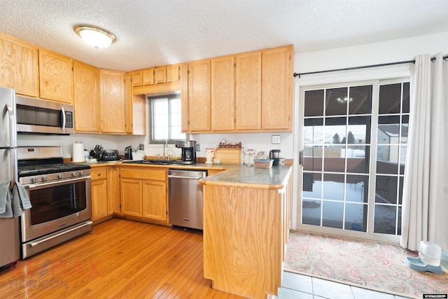 kitchen featuring appliances with stainless steel finishes, light brown cabinetry, sink, and light hardwood / wood-style flooring