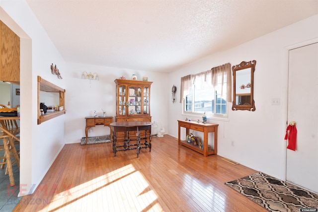 dining space with hardwood / wood-style floors and a textured ceiling