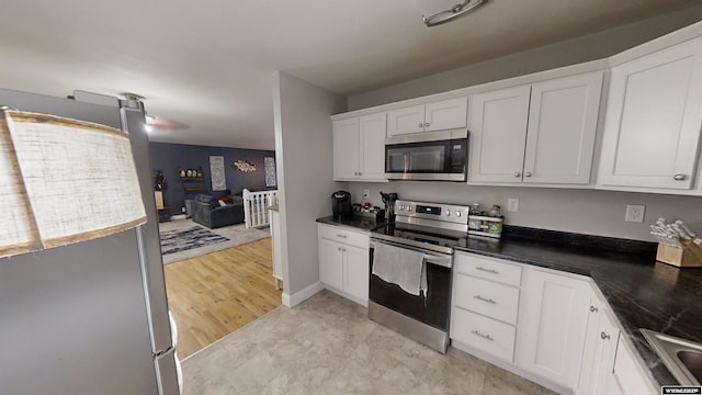 kitchen featuring sink, light hardwood / wood-style flooring, white cabinetry, dark stone countertops, and stainless steel appliances