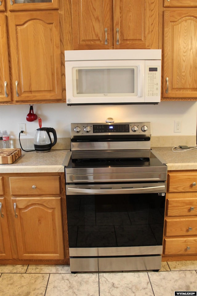 kitchen with stainless steel range with electric stovetop, light countertops, and white microwave