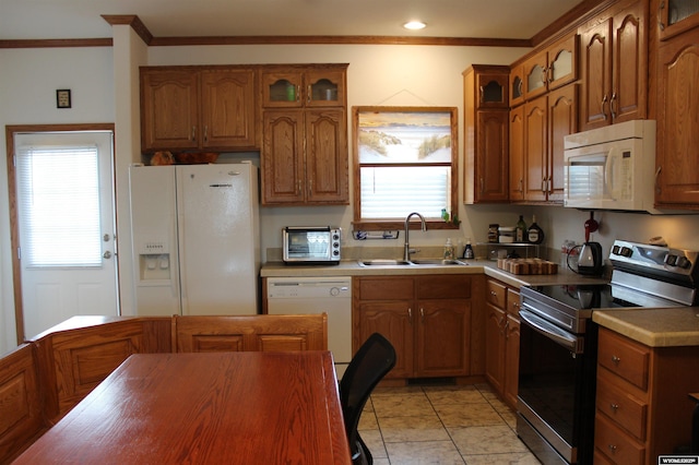 kitchen featuring white appliances, crown molding, brown cabinets, and a sink