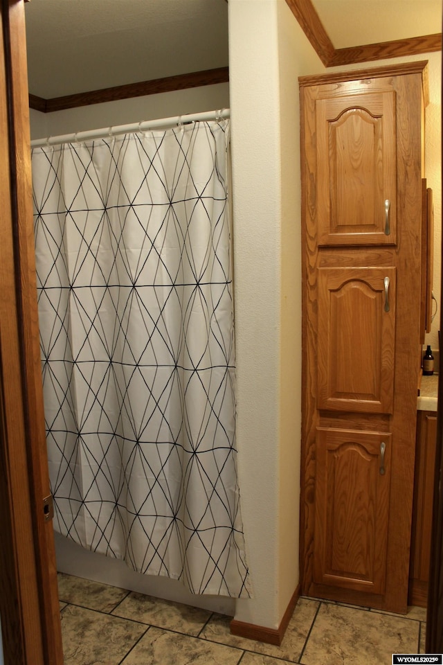 bathroom with ornamental molding, shower / bath combination with curtain, and baseboards