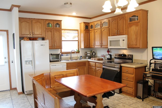 kitchen with white appliances, brown cabinetry, a sink, and crown molding