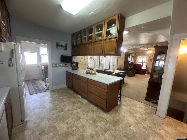 kitchen with white fridge, light carpet, a kitchen breakfast bar, and kitchen peninsula