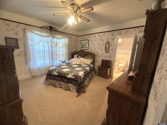 carpeted bedroom with ensuite bathroom and ceiling fan