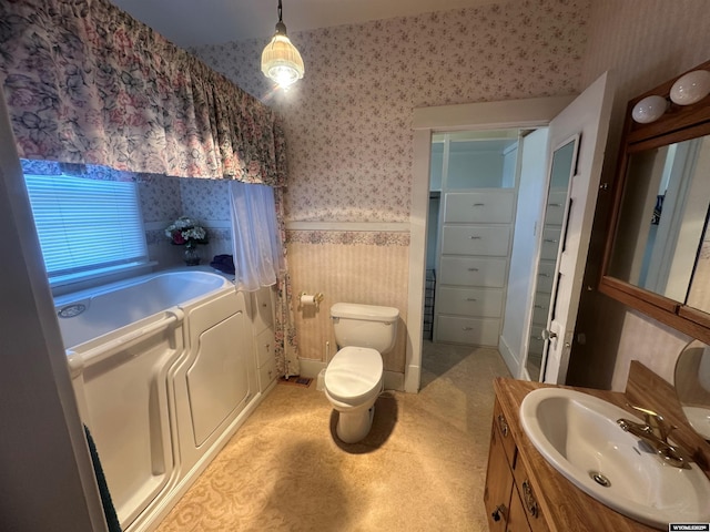 bathroom featuring vanity, a tub to relax in, independent washer and dryer, and toilet