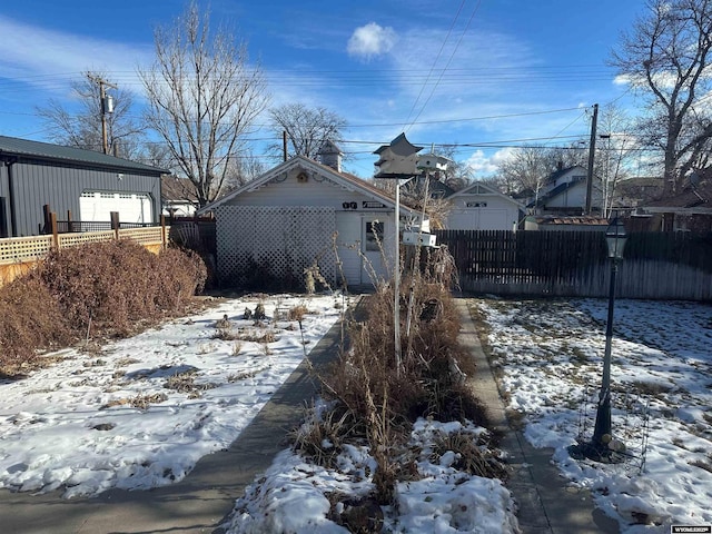 yard layered in snow with an outbuilding and a garage