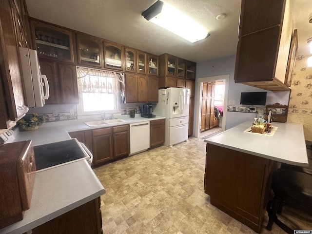 kitchen featuring white appliances, kitchen peninsula, and sink