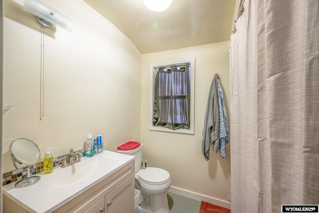 bathroom with vanity, toilet, and lofted ceiling