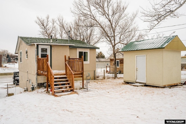 snow covered house featuring a storage shed