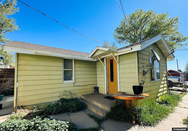 single story home with a shingled roof and fence