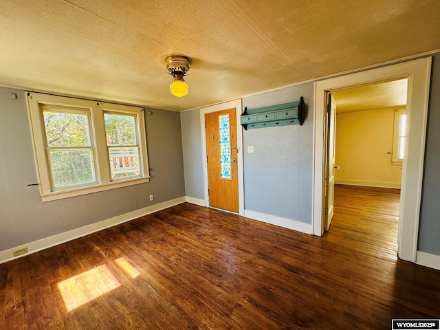 spare room featuring dark wood-style floors, baseboards, and a textured ceiling