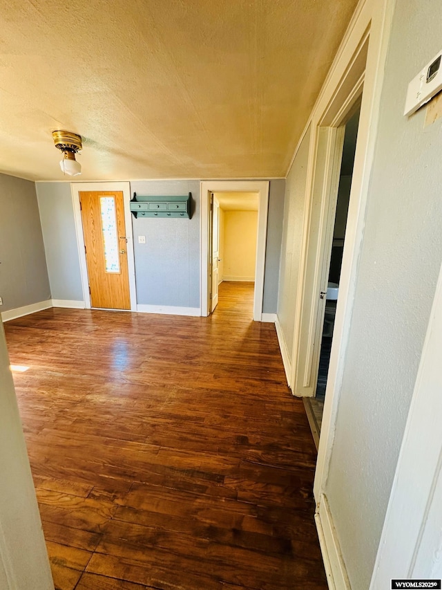 interior space featuring dark wood-style floors, a textured ceiling, and baseboards