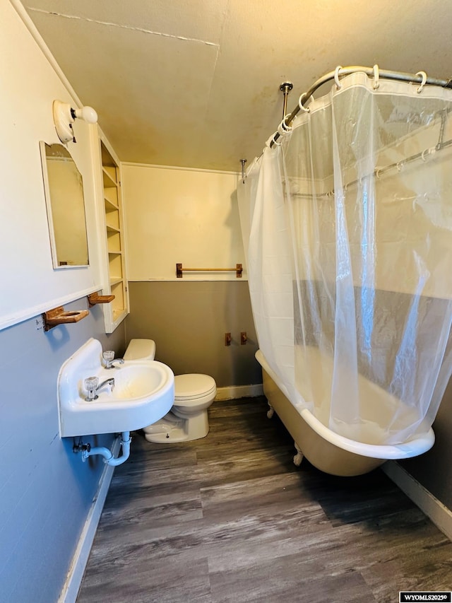 full bathroom featuring toilet, wood finished floors, a sink, baseboards, and shower / bath combo