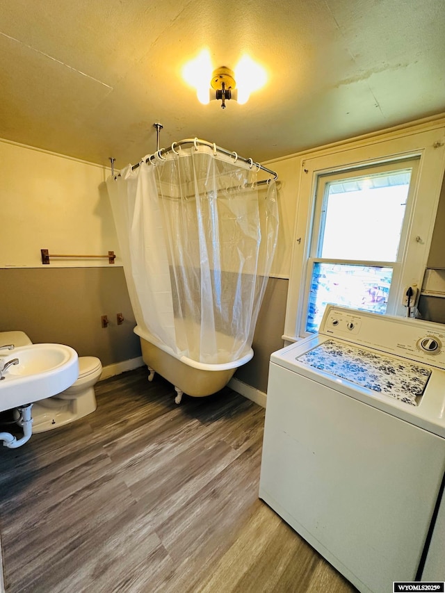 washroom with laundry area, wood finished floors, washer / dryer, and baseboards