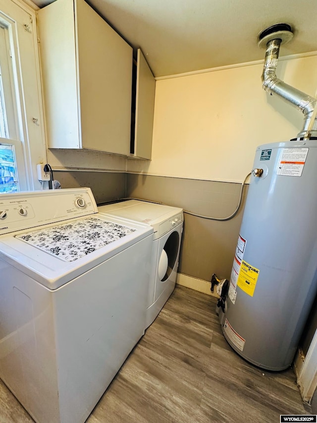 laundry room featuring cabinet space, baseboards, wood finished floors, washer and dryer, and water heater