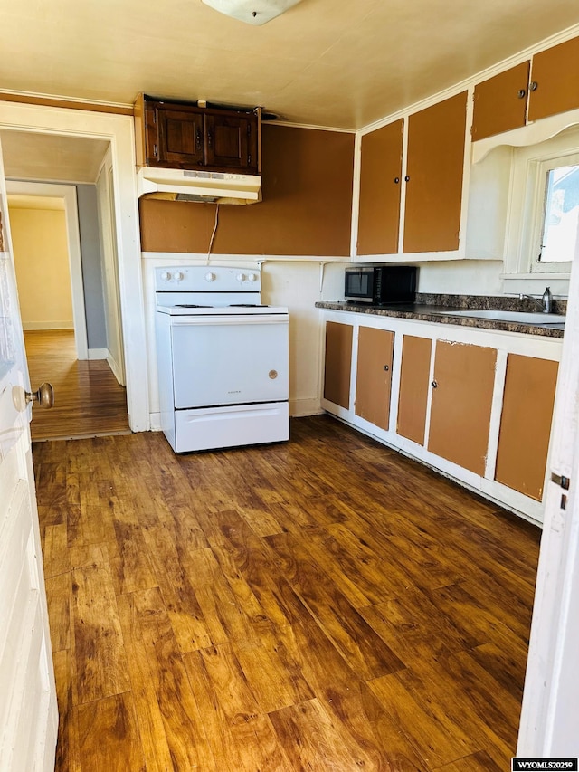 kitchen with white range with electric stovetop, dark countertops, dark wood-type flooring, under cabinet range hood, and a sink