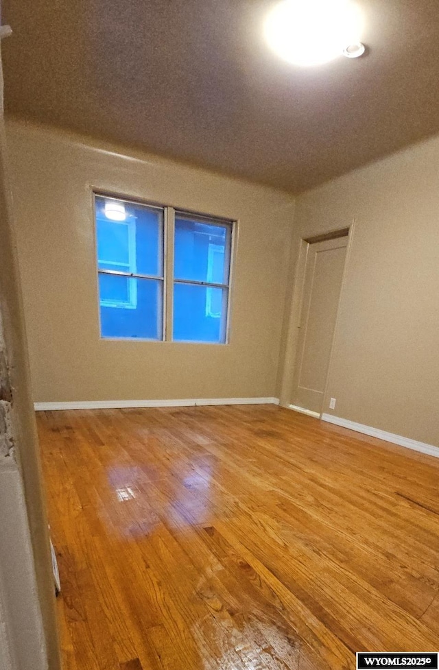 unfurnished room with baseboards and wood finished floors