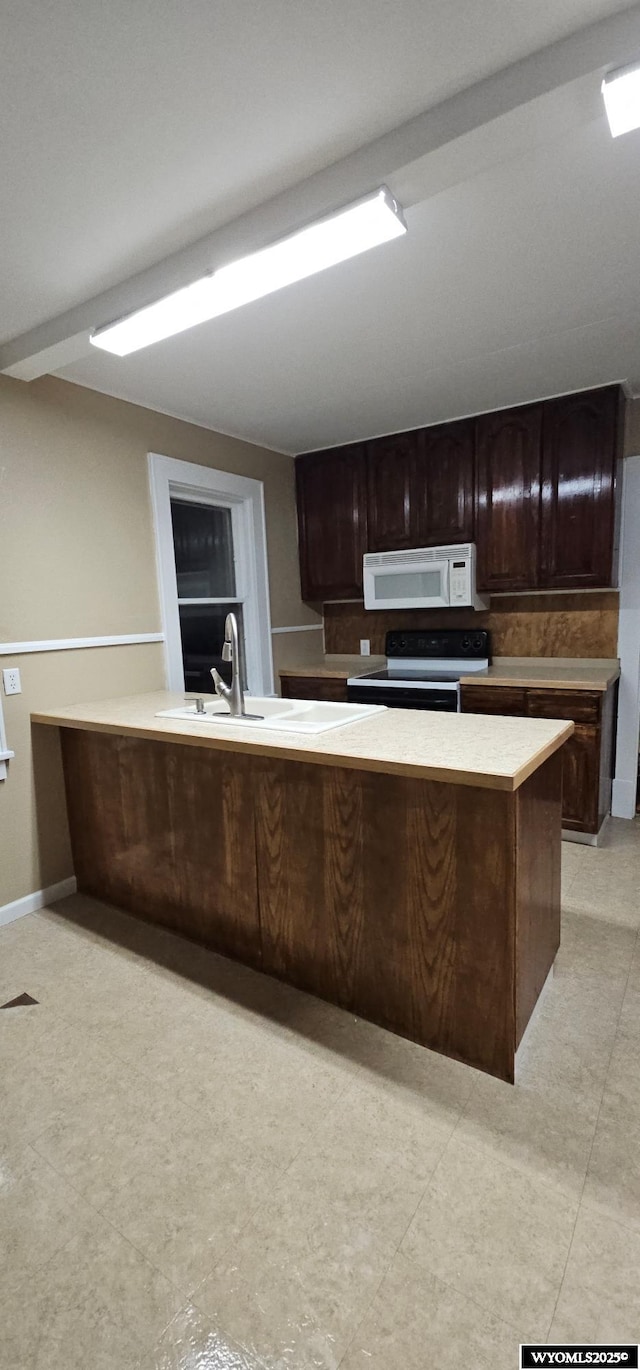 kitchen with electric range, white microwave, light countertops, dark brown cabinets, and a sink