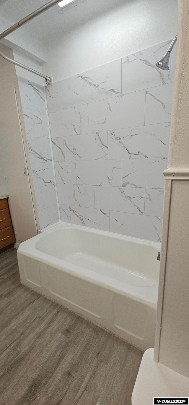 bathroom featuring bathtub / shower combination, wood finished floors, and toilet