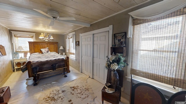 bedroom featuring crown molding, wood ceiling, light hardwood / wood-style floors, ceiling fan with notable chandelier, and a closet