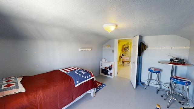 bedroom featuring lofted ceiling, a textured ceiling, and concrete floors