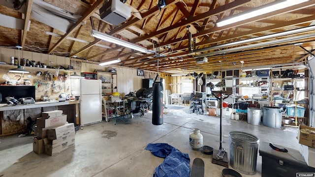 garage featuring a garage door opener, white fridge, and a workshop area